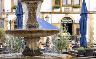 Das Bild zeigt den Brunnen auf dem Historischen Marktplatz in Peine. Im Hintergrund sieht man das alte Rathaus. 