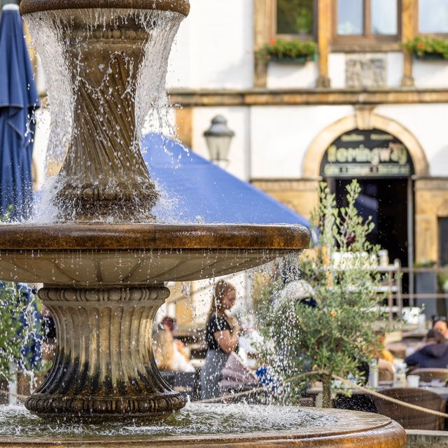 Das Bild zeigt den Brunnen auf dem Historischen Marktplatz in Peine. Im Hintergrund sieht man das alte Rathaus. 