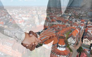 Das Bild zeigt eine Luftaufnahme von Peine darüber sind zwei Personen, die sich die Hand reichen. 