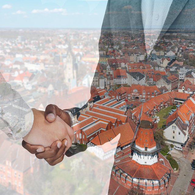 Das Bild zeigt eine Luftaufnahme von Peine darüber sind zwei Personen, die sich die Hand reichen. 