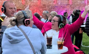 Das Bild zeigt tanzende Menschen im Burgpark in Peine im Discolicht bei der Silent Music Party in Peine. 